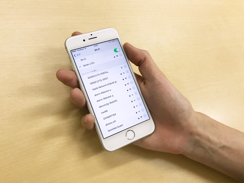 a hand holding a phone connected to the genki mobile pocket wifi