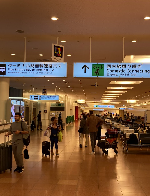 Haneda Airport hallway to the JAL ABC counter with signs for domestic connections and Free Shuttle Bus to Terminal 1,2