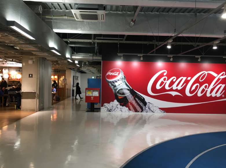 Narita Airport Terminal 3 departures area with Coca-Cola wall display.