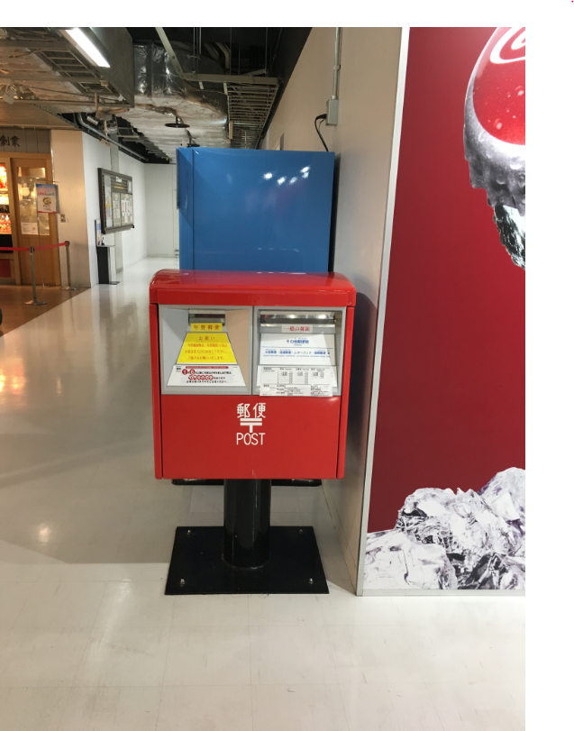 Narita Airport Terminal 3 red postbox near the Coca-Cola wall.