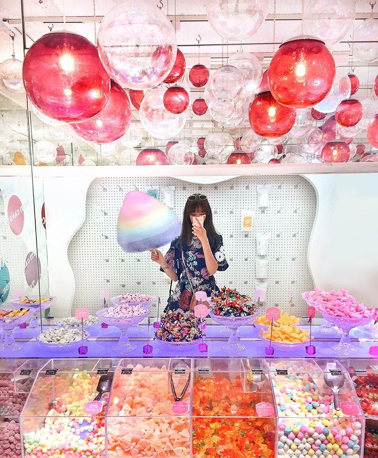 Girl holding cotton candy at a colorful Totti Candy Factory